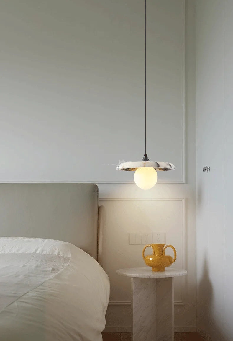 Black LED Marble Pendant Light above a bedside table with a yellow vase, adding a warm and modern lighting accent to the bedroom.