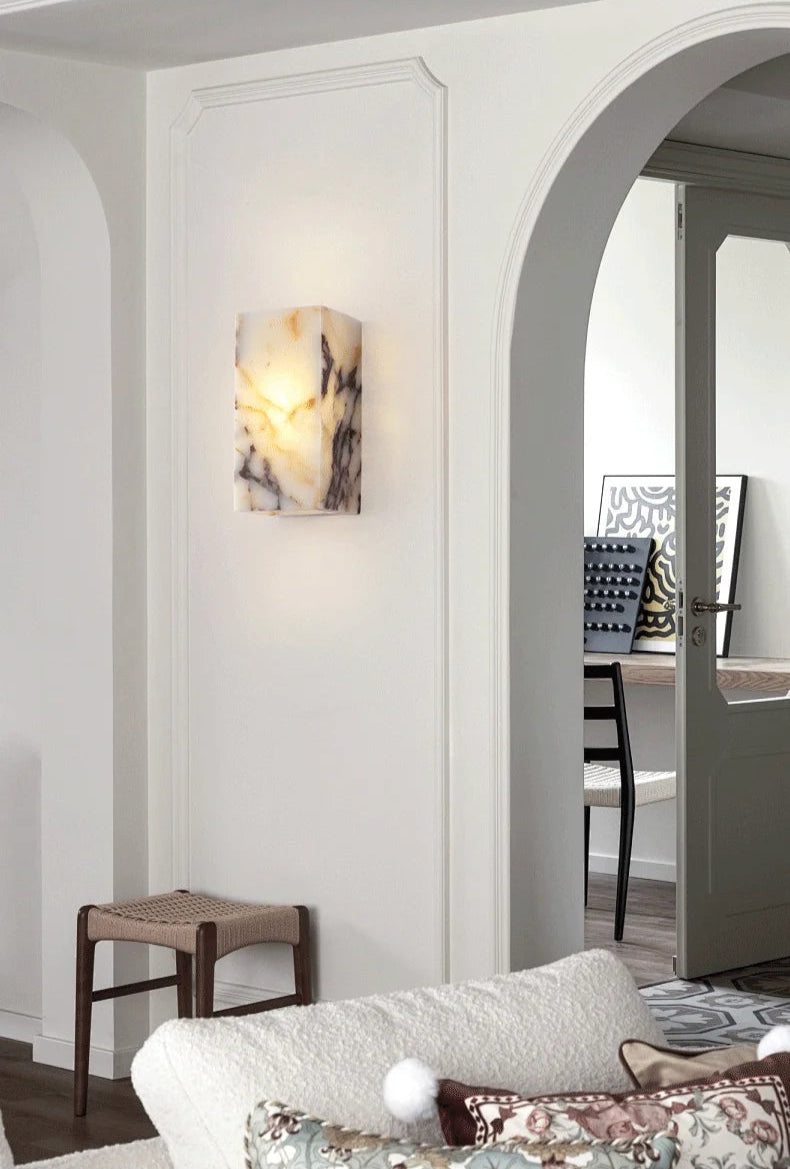 Black marble stone wall lamp illuminating a modern living space, ideal for luxury bedroom or hallway lighting.