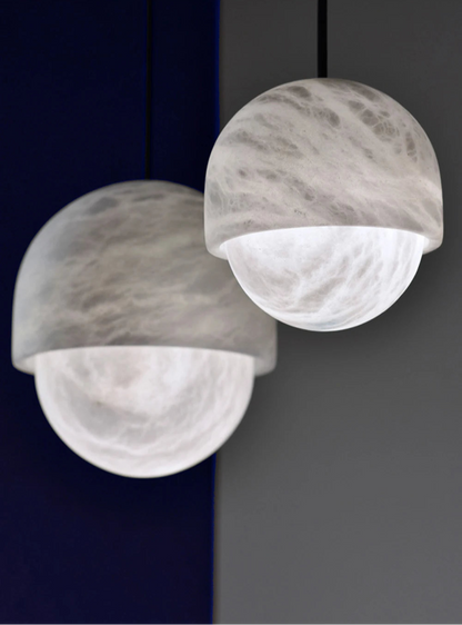 Close-up of two dome-shaped marble LED pendant lights. Marble LED pendant light – modern ceiling lamp dimmable for soft interior lighting.