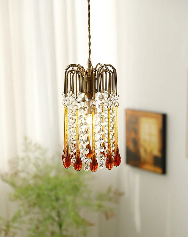 Elegant vintage chandelier with amber glass drops and crystal accents, suspended in a softly lit bedroom setting.