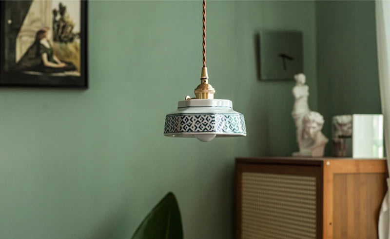 Elegant ceramic pendant lamp with blue pattern and LED lighting, hanging in a modern room with artistic decor.