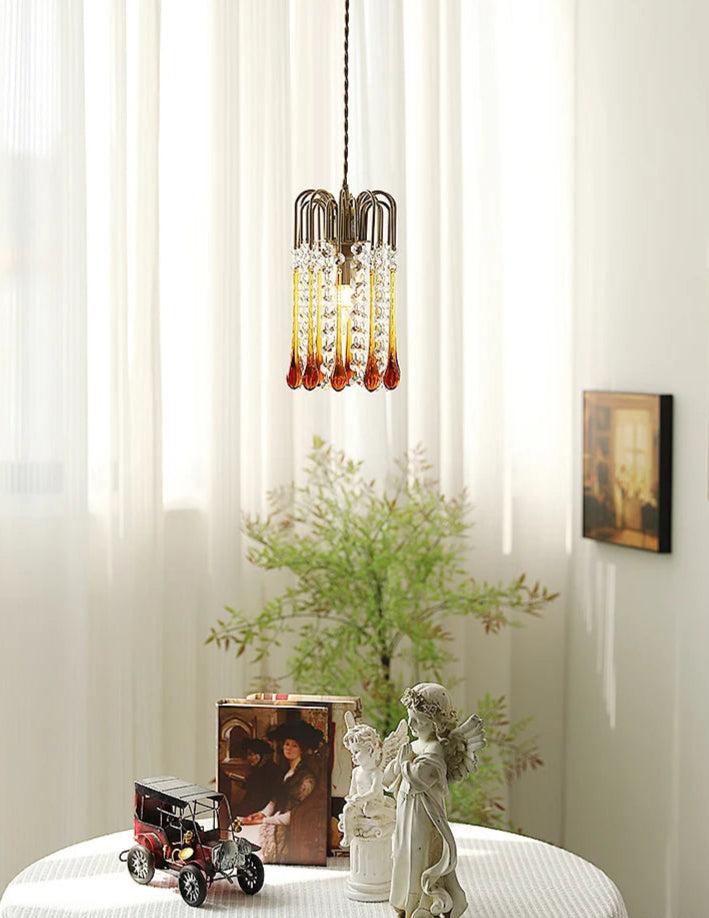 Copper pendant chandelier with vintage water drop glass, enhancing a cozy room with natural light and classic decor.