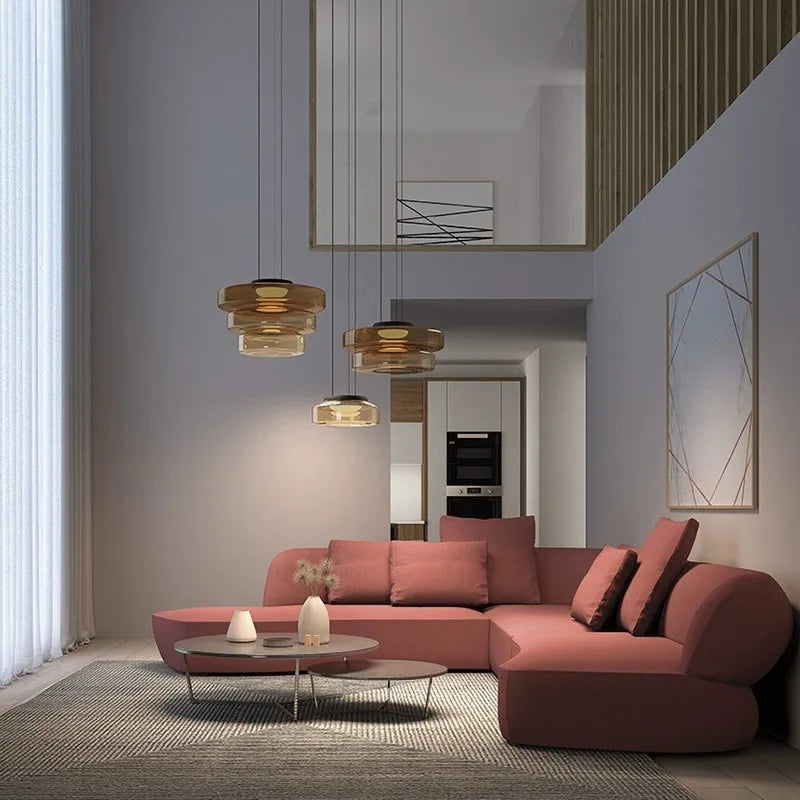 Modern living room with luxury green and amber glass pendant lights above a pink sectional sofa. Ideal for upscale home decor.