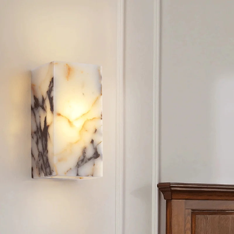 Contemporary black marble wall lamp with soft LED lighting, mounted above wooden headboard for elegant bedroom decor.