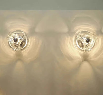 Pair of designer LED glass wall lamps casting ambient light patterns, suitable for modern interiors and commercial spaces.