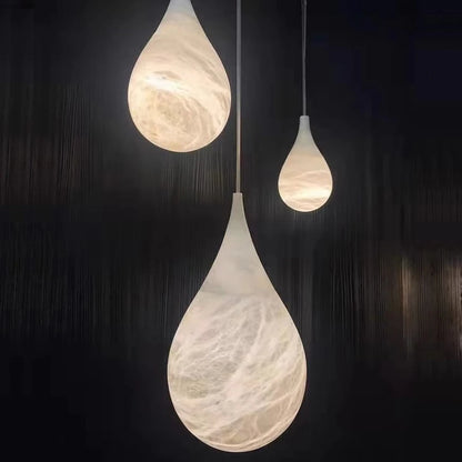 Three teardrop marble LED pendant lights glowing in dark room. Marble LED pendant light – modern ceiling lamp dimmable for cozy ambiance.
