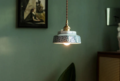 Vintage-style ceramic pendant lamp with blue pattern and LED bulb, suspended in a cozy, modern living room.