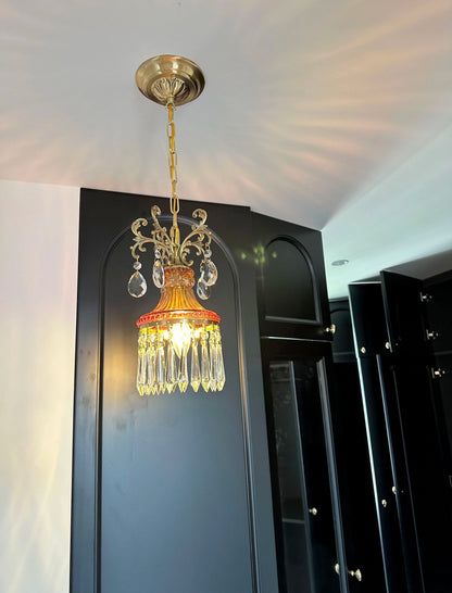 Luxury French crystal chandelier with warm glow, retro pendant light enhancing black paneled room décor.