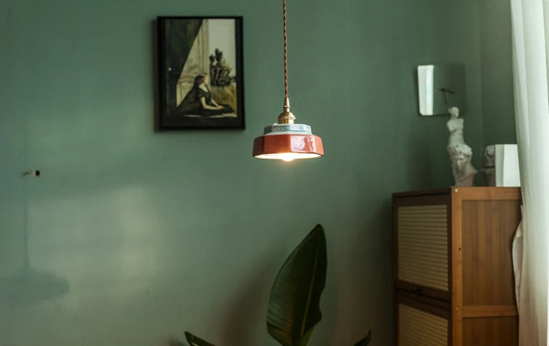 Vintage ceramic LED pendant lamp with copper detailing, softly illuminating a green-toned living space with modern elegance.