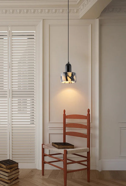 Single Black Marble Pendant Light with Nordic LED hanging above a wooden chair, casting warm light in a cozy corner.