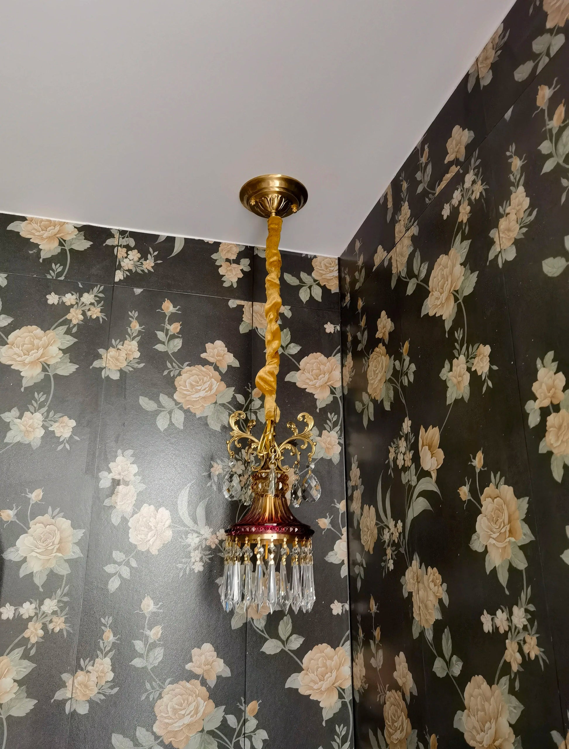 Vintage-style French crystal chandelier with twisted cord mount, luxury pendant light for floral wallpapered room.