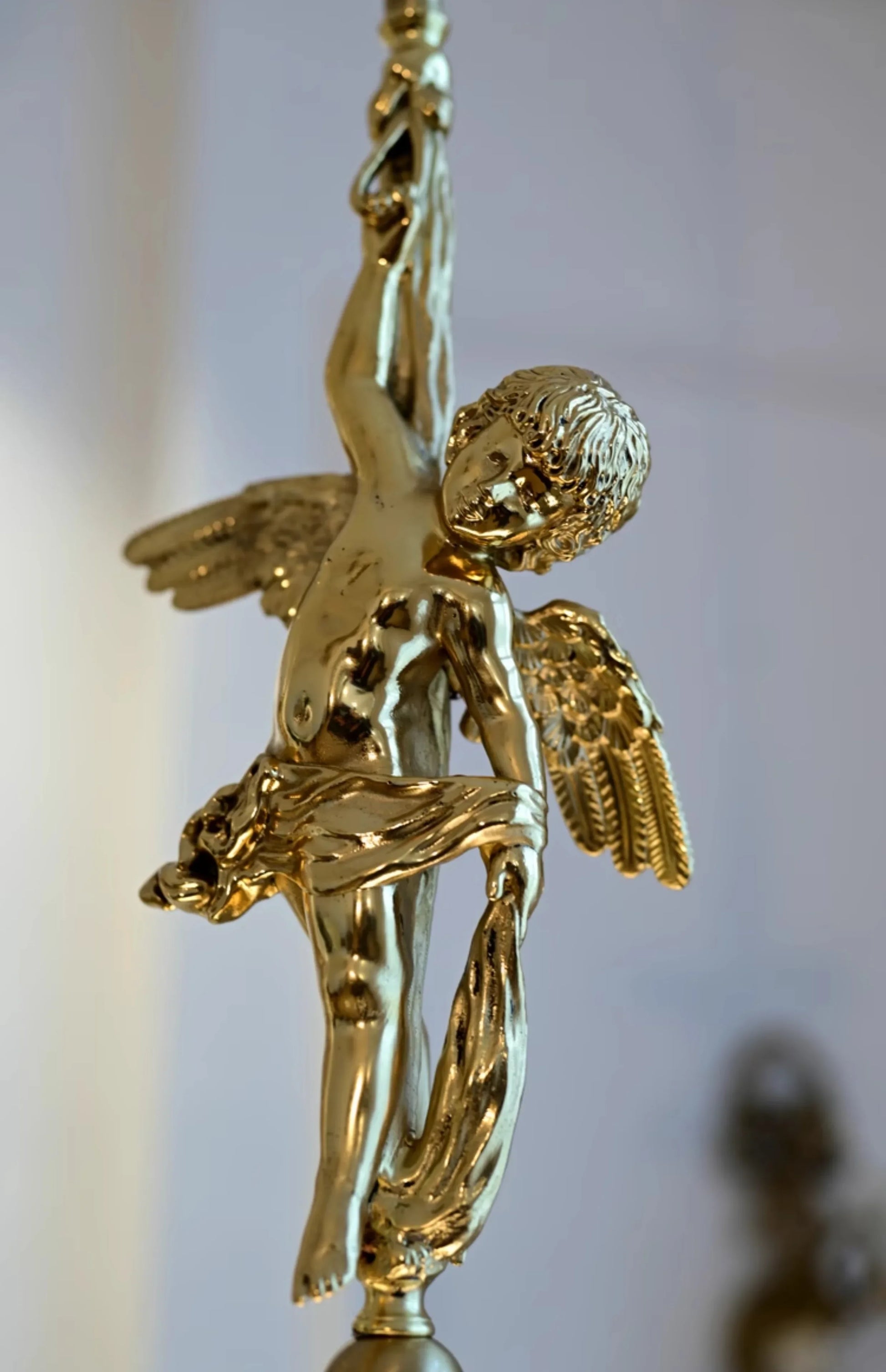 Close-up of gold copper angel figure on modern pendant light, showcasing intricate detailing for luxury home lighting fixtures.