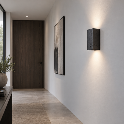 Black stone wall light photographed from a low angle in a minimalist hallway