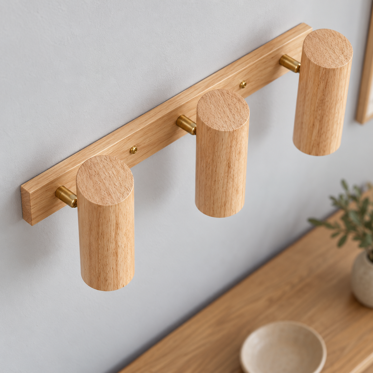 Elevated detail of three natural rubberwood wall spotlights, showing upper wood faces and brass pivots