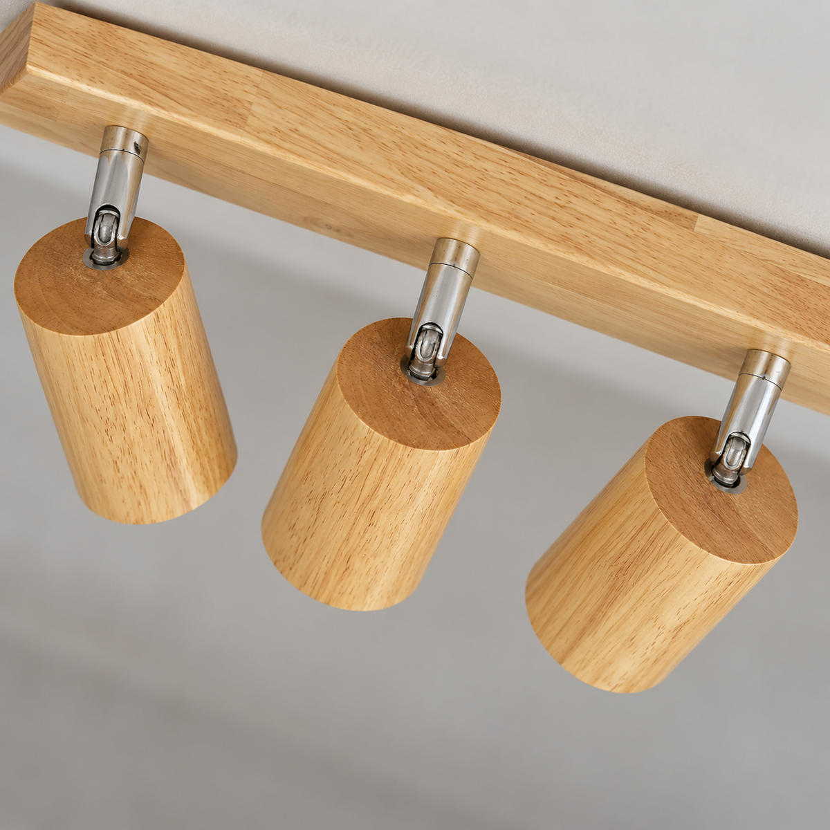 Elevated close detail of three natural wood ceiling spotlights, showing upper wood faces and chrome pivots