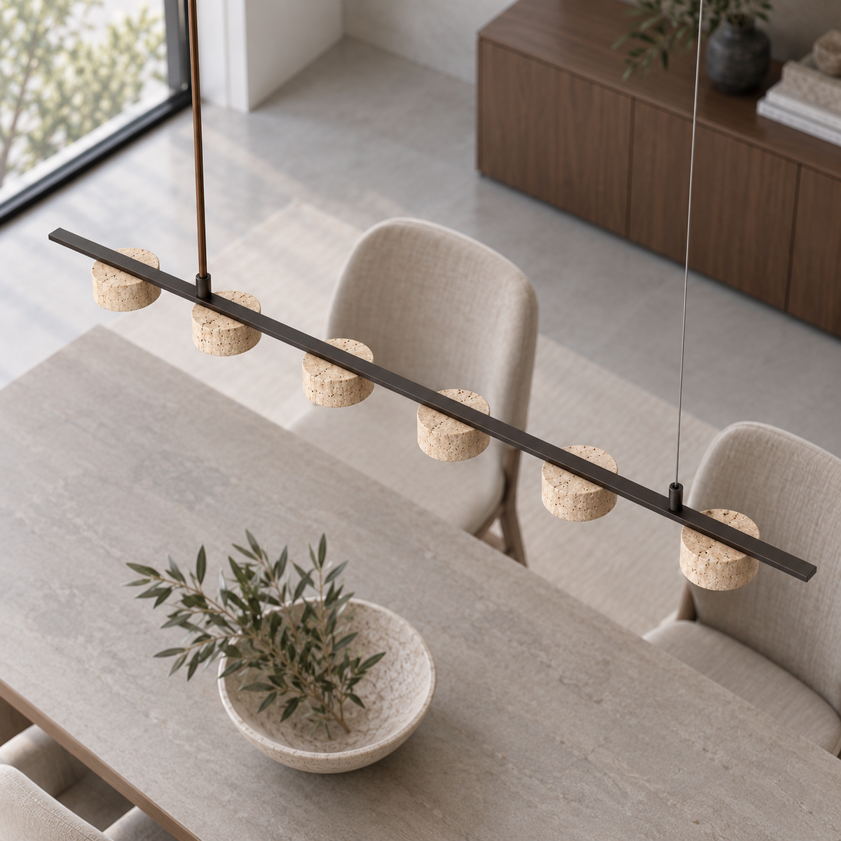 Six cylindrical stone shades beneath a slim pendant rail, seen from above with the asymmetric rod and wire suspension