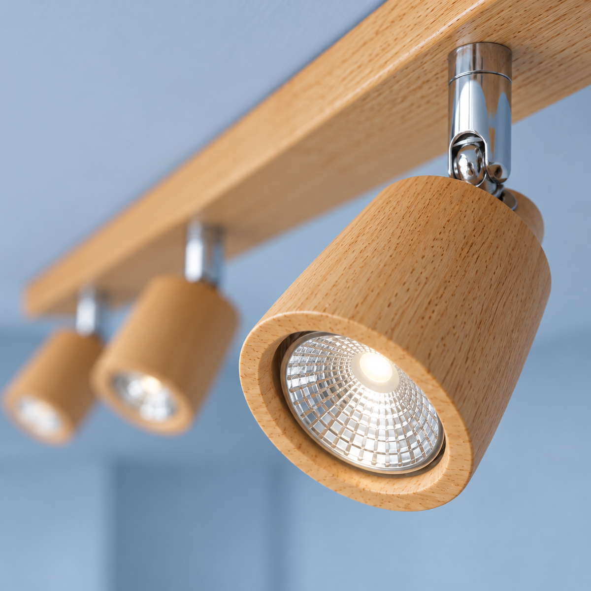 Wood ceiling bar with pivoting spotlights — Wood beige, right end recessed reflector and chrome hinge detail, illuminated