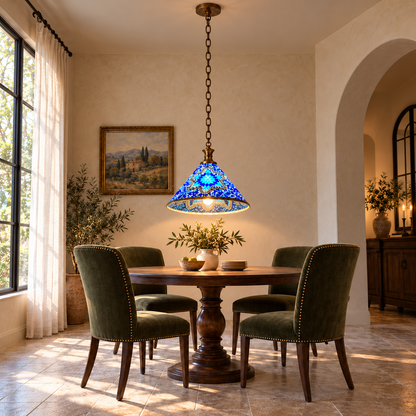 Blue Style A mosaic cone pendant, illuminated above a dining table from a low frontal view, with its hollow underside and complete ceiling suspension visible.