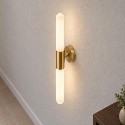 Frosted white and gold two-rod wall light, illuminated and visibly mounted, viewed from a medium elevated right position with the top sleeve entry and rear support visible.