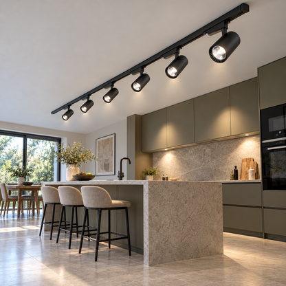 Six illuminated black track spotlights mounted on a continuous kitchen ceiling rail, photographed from a distant low end angle.