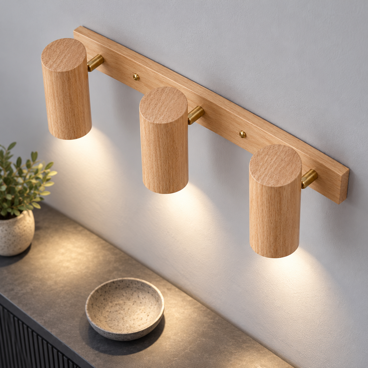 Above view of three beige rubberwood wall spotlights with brass pivots casting downward light