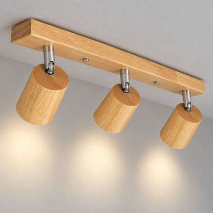 Upper head view of three rubberwood chrome-pivot ceiling spotlights casting light on pale grey wall