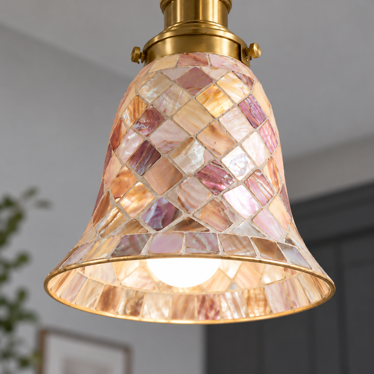 Close underside detail of lit iridescent shell mosaic bell, showing pearl facets, grout and gold lower rim.