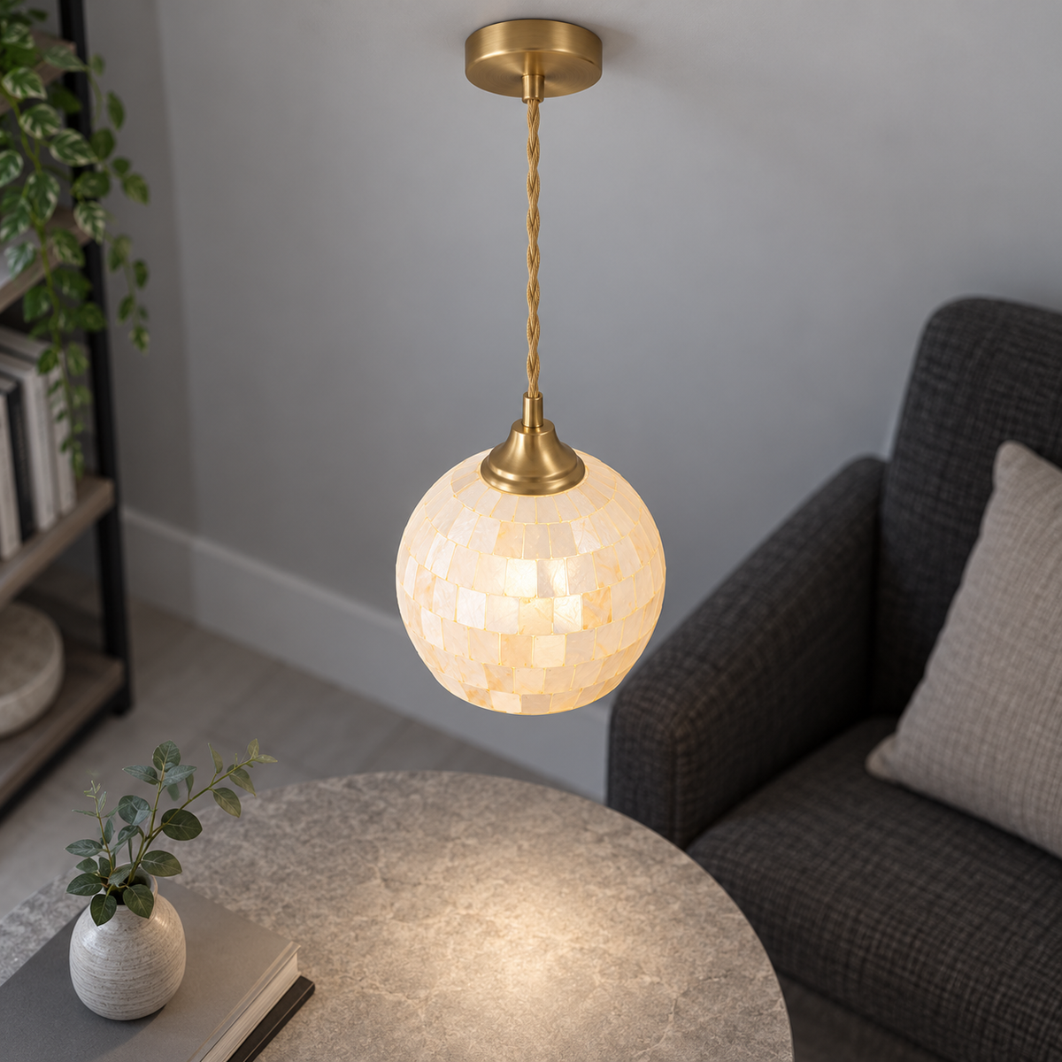 Lit ivory shell globe pendant centred from an elevated oblique view, with gold cord and canopy in a grey room.