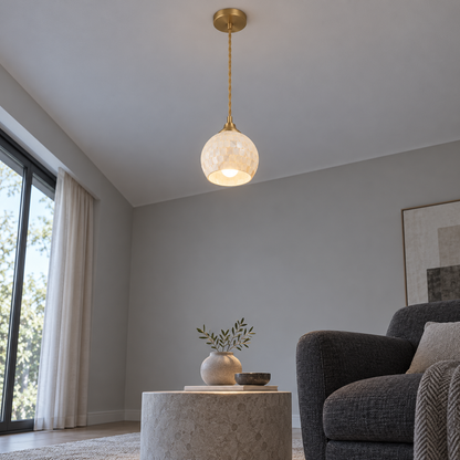 Ivory shell globe pendant lit and ceiling-mounted, seen from a distant low angle across a minimal grey room.