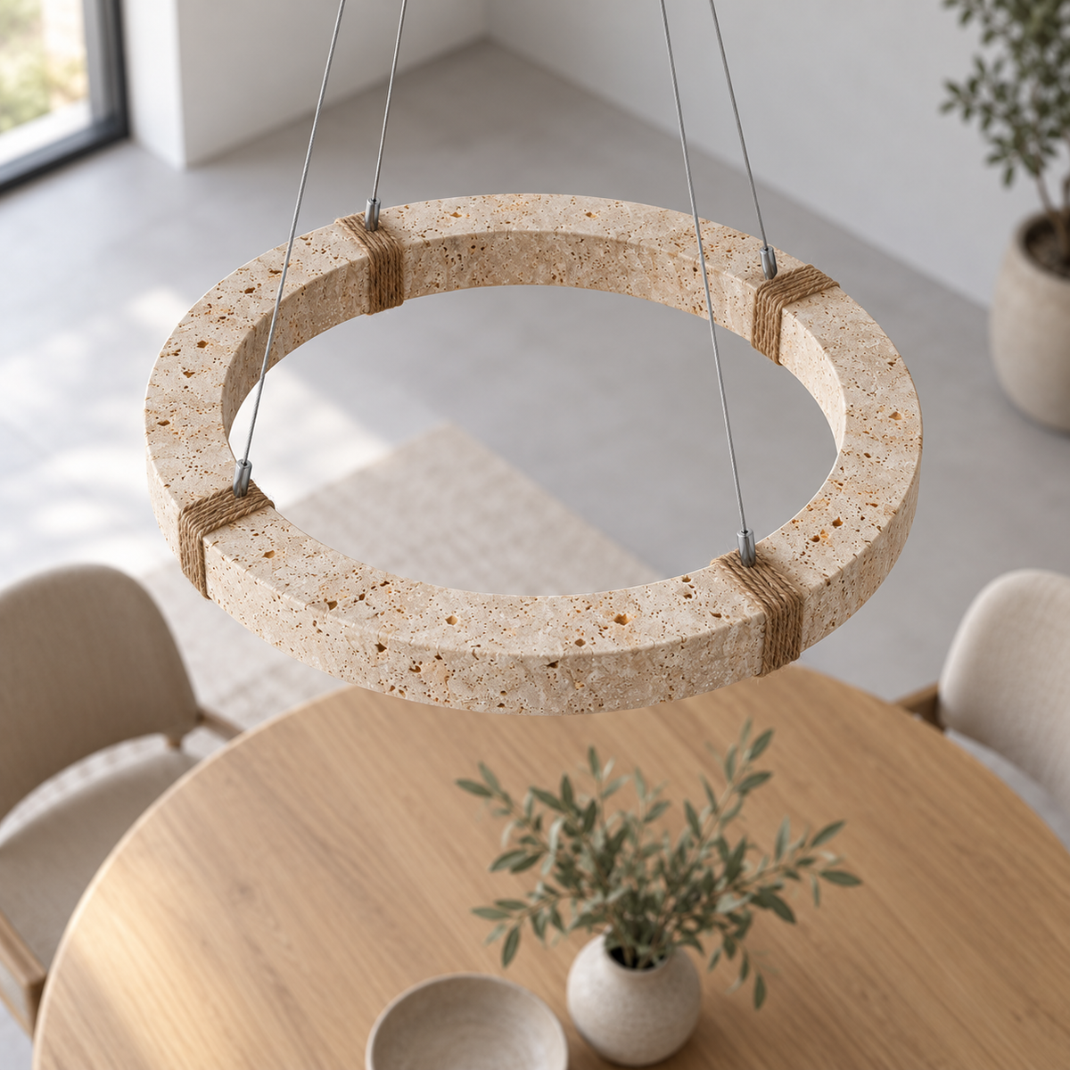 Elevated view of the 40 cm travertine ring pendant showing its stone top and rope wraps above a dining table