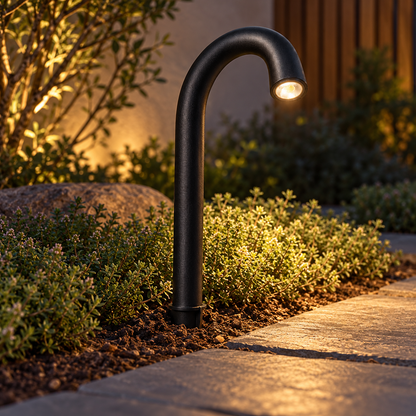 Curved aluminium path light with a downward glow, Black | Height 40 cm · Ground spike, installed outdoor photograph