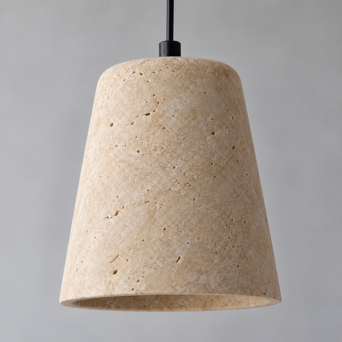 Close-up of honed travertine stone and black cord attachment on a tapered pendant shade