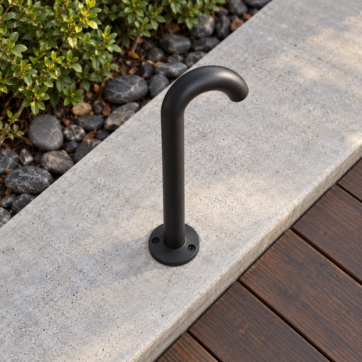 High oblique view of the black curved aluminium path light installed on a concrete step, with its downward lens hidden