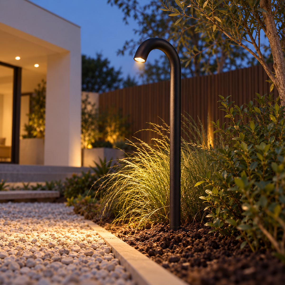Low underside view of a curved black path light installed in a garden border