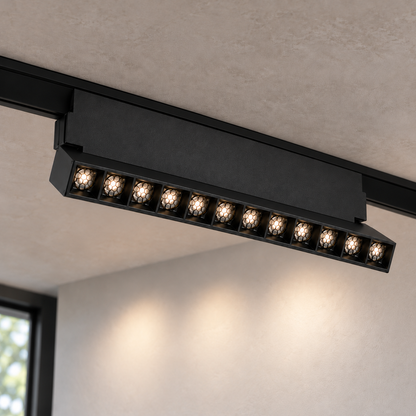 Magnetic folding grille light 12W, black finish, with twelve illuminated recessed honeycomb optics and visible hinge support, installed in a ceiling track.