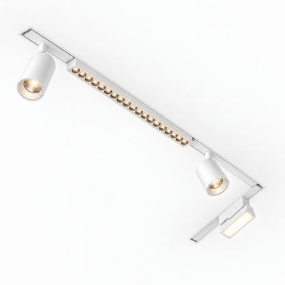 White slim magnetic track lighting installed in an L-shaped recessed ceiling layout, with warm-lit spotlights, grille and folding floodlight; example configuration.