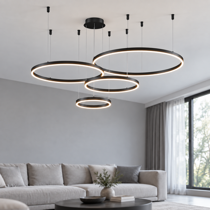 Black suspended LED ring chandelier with four offset horizontal rings, 40, 60, 80 and 100 cm diameters, illuminated in a neutral modern living room.