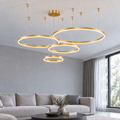 Gold suspended LED ring chandelier with four offset horizontal rings, 40, 60, 80 and 100 cm diameters, illuminated in a neutral modern living room.